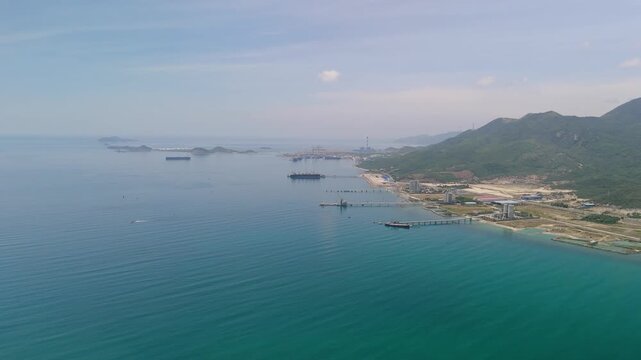 People enjoy the beach at Dok Let in Vietnam. The video shows clear blue water, distant hills, and boats a little farther away. It captures a sunny day at a popular spot in Vietnam
