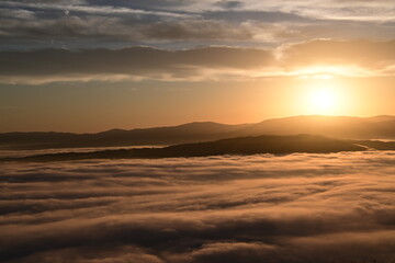 Fototapeta premium stunning sunrise between the fog and clouds in the coastal mountains