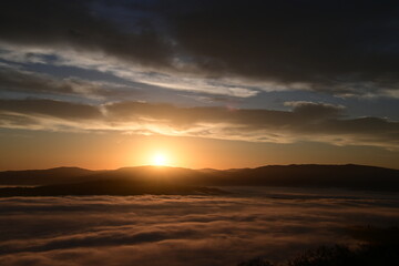 Fototapeta premium cloudy sunrise above the fog and below the clouds