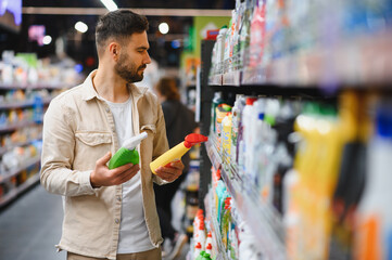 Man choosing cleaning supplies in supermarket aisle