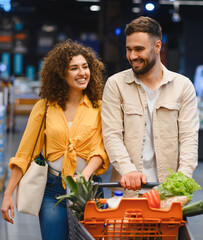 Happy couple enjoying grocery shopping in supermarket aisle