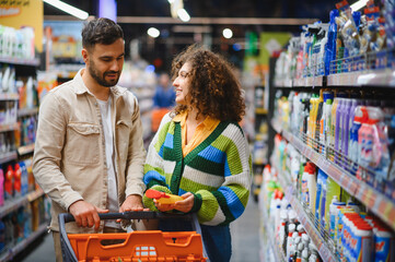 Couple shopping for cleaning supplies in supermarket aisle