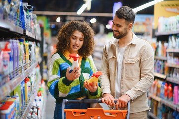 Couple comparing cleaning products in supermarket aisle