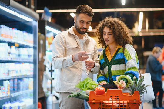 Couple checking shopping list buying groceries in supermarket