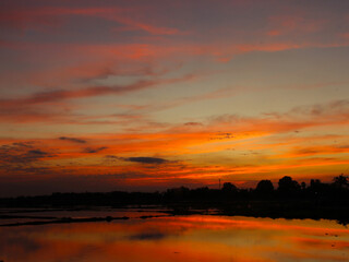 Obraz premium The reflection of the sun on the water in the rice fields in the evening is a beautiful, natural sight.