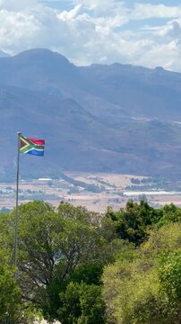 South Africa landscape, 4K video of a waving South African Flag outdoor at daytime during summer in Paarl with stunning view on mountains of the Cape Winelands with space for text.