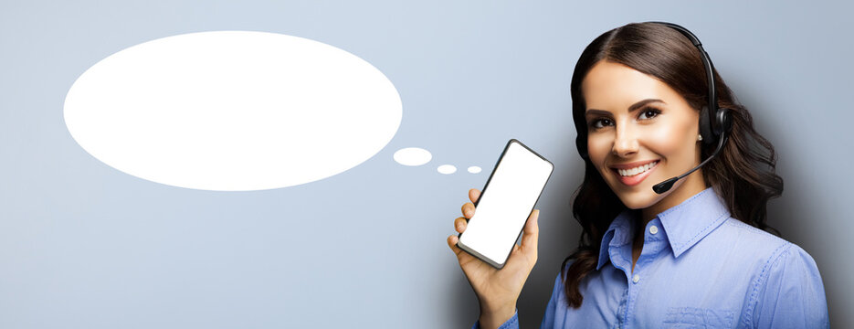 Customer support callcenter call center operator woman in headset hold show point smartphone cell mobile phone white blank screen isolated gray grey background. Empty mockup speech bubble speechbubble