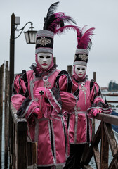 Obraz premium Masked people in ornate detailed handmade masks and costumes pose for the camera during the annual Venice Carnival, Italy, February 2026. 