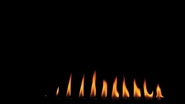 Several diferent sized small flames emerge from a gas bar.