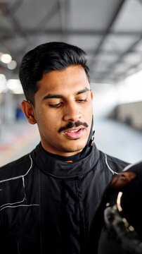 Man in racing helmet adjusts visor with hand, focused stare