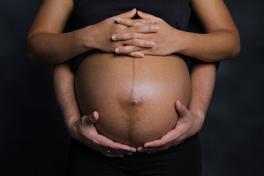 Photo concept of pregnant mother and husband. No faces, only the hands of husband and wife as a language of "love for their child in the womb".