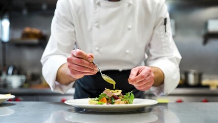 Fototapeta premium Professional chef plating salad in restaurant kitchen.