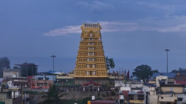 Cinematic drone view of golden Sri Chamundeshwari Temple atop Chamundi Hills on misty day