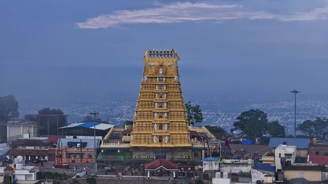 Cinematic drone view of golden Sri Chamundeshwari Temple atop Chamundi Hills on misty day