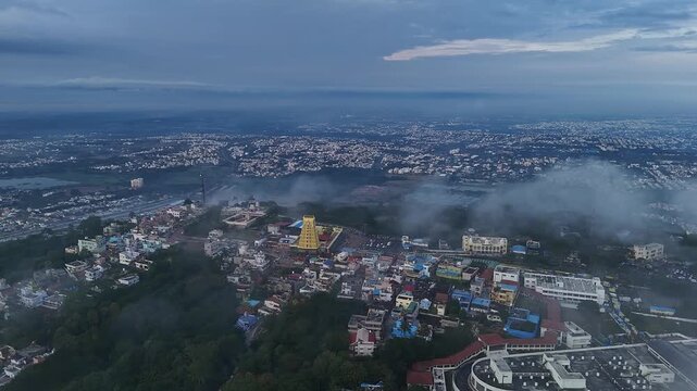 Cinematic drone view of Sri Chamundeshwari Temple atop Chamundi Hills amid misty cityscape in mysore