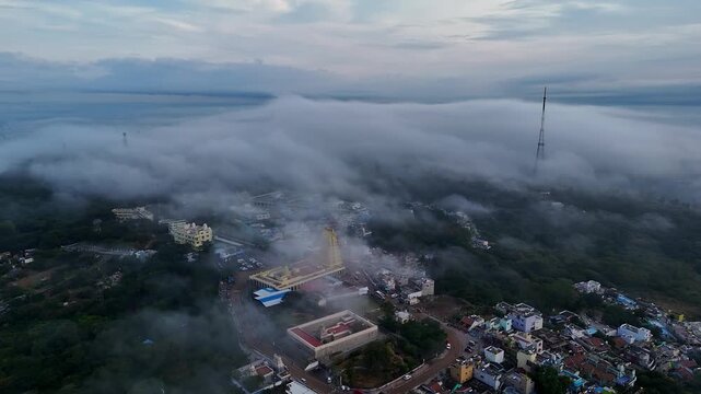 Cinematic drone view of Sri Chamundeshwari Temple atop Chamundi Hills amid misty cityscape in mysore