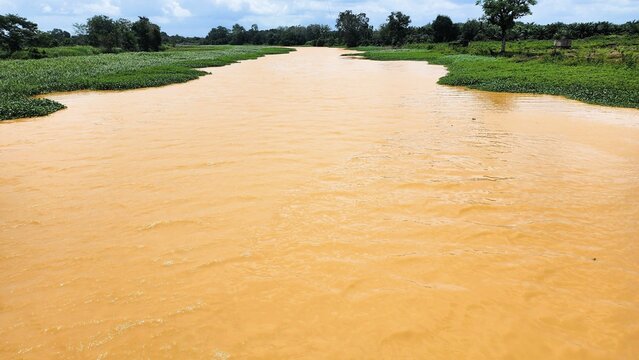 A river with brown water, polluted by environmentally damaging mining activities.