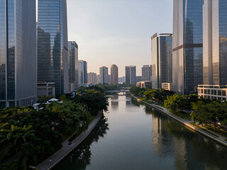 Panoramic View of Modern Skyscrapers Lining a Calm River at Golden Hour with Lush Greenery Along Waterfront Urban Landscape Cityscape Architecture