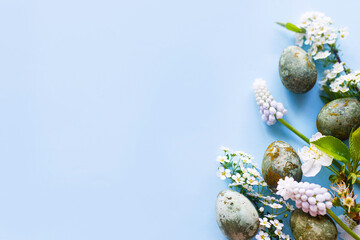 Easter flat lay. Stylish easter eggs and cherry flowers on blue background. Easter celebration, season greetings mockup. Spring modern floral banner © sonyachny