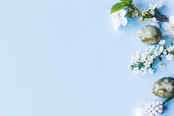 Easter flat lay. Stylish easter eggs and cherry flowers on blue background. Easter celebration, season greetings mockup. Spring modern floral banner © sonyachny