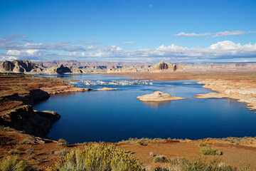 Panoramic view of Lake Powell with boats and dramatic desert canyon landscape under blue sky with clouds in Arizona, USA. Scenic American Southwest nature travel destination. © Duro Mesiar