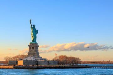 Fototapeta premium Liberty's Embrace: Witness the iconic Statue of Liberty, standing tall against a clear sky. A symbol of freedom and hope, her majestic presence is captured in the soft light of dawn.
