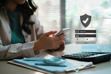Businesswoman using smartphone with secure login interface and digital shield icon, representing cybersecurity, data protection, identity verification, and safe access for online banking and financial