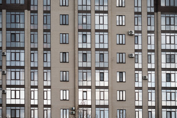 Fototapeta premium Close-up view of a residential building exterior with glass balconies and air conditioners. Modern real estate development. Abstract architectural background 