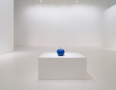 Minimal white room with one blue apple