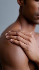 Close-up of a man touching his shoulder highlighting skin care, body awareness and health concept.