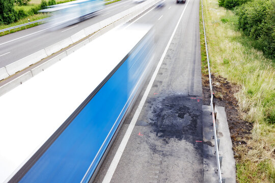 Brandschaden auf Autobahnbelag von ausgebranntem Auto mit vorbeifahrendem Verkehr