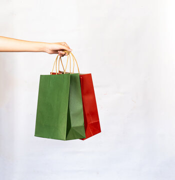 Hand holding paper shopping bag color red green two on white background.