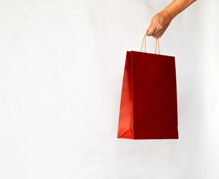 Hand holding paper shopping bag red color on white background.