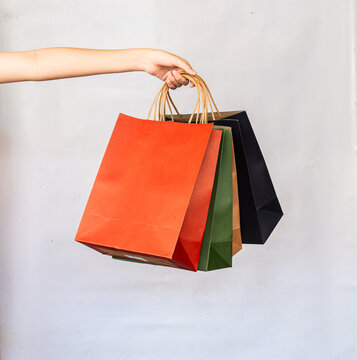Hand holding paper shopping bag colorful four on white background.