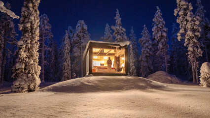 Cozy cabin nestled in snowy Lapland landscape at night in Akaslompolo, Finland