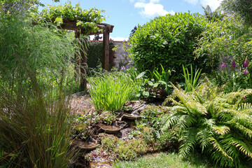 A tiered waterfall cascades through a lush, vibrant garden setting. © Ankur