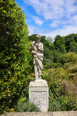 Fototapeta premium A stone statue of a mythological figure stands prominently in a lush garden setting.
