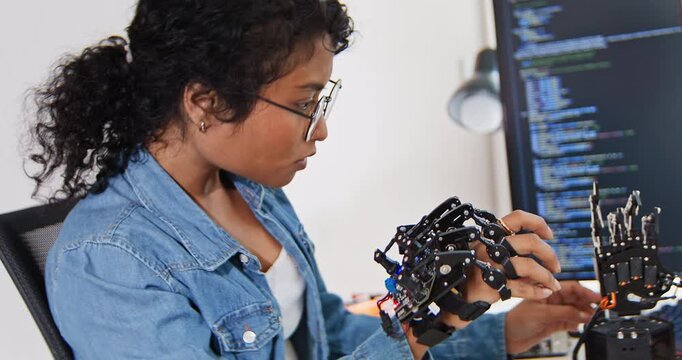 South east asian female engineer developer examine robotic arm with laptop computer at home office. Science and technology, Robot automated innovation, Electrical engineering manufacturing concept