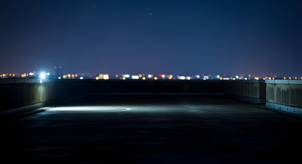 Fototapeta premium Rooftop view of a distant city skyline at night with illuminated buildings and a dark foreground under a clear starry sky