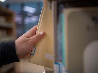 Hand reaching for a book from the shelf © Dong