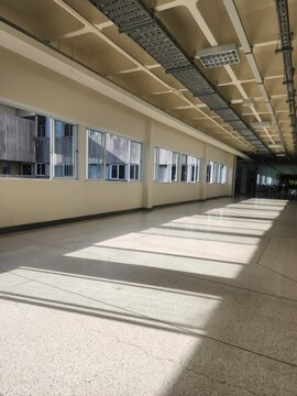 Empty hospital corridor with sunlight streaming through windows on polished terrazzo floor in modern medical facility