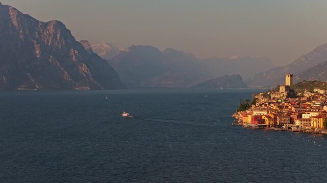 Veduta aerea da drone del paese di Malcesine sulle sponde del Lago di Garda in provincia di Verona in Italia nel mese di marzo con un traghetto in navigazione