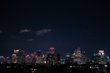 Night cityscape of a modern metropolis with glowing office building lights and skyscrapers. Urban skyline under a dark sky, representing business districts, city life, and night architecture.