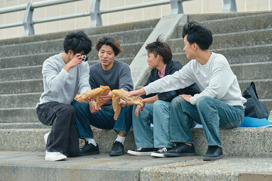 屋外で一緒に食事をする若い男性たち