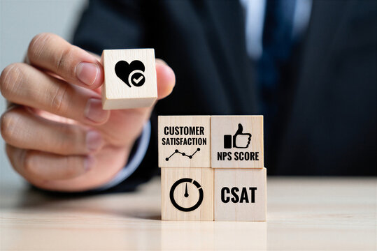 Business person holding a wooden block with customer satisfaction icons representing feedback and performance metrics