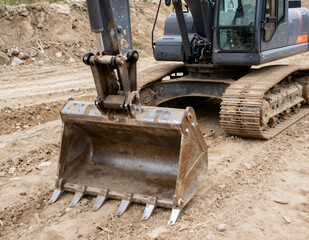 Fototapeta premium Heavy Machinery Excavator Bucket and Tracks on Construction Site with Dirt Ground Close-up Realistic Photo for Engineering or Infrastructure Projects