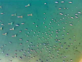 Aerial view of traditional Vietnamese fishing boats scattered across turquoise tropical bay from above.