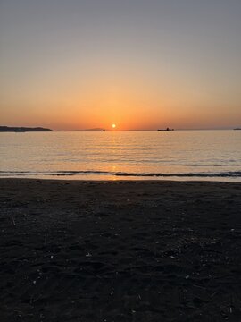 The exact moment of sunset over the calm ocean with a golden light reflection on the sandy beach in Tateyama