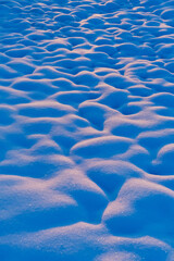 Snow texture in winter twilight captured during blue hour with soft sunset light creating natural shadows patterns and peaceful cold atmosphere outdoors
