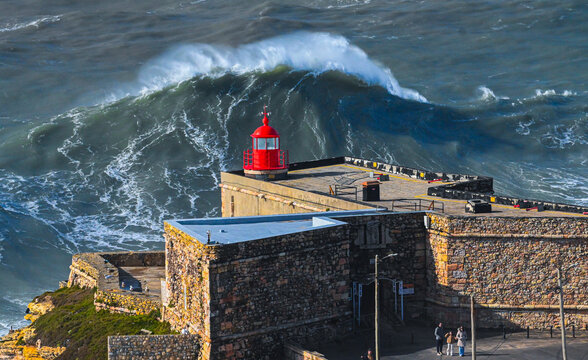 Giant Atlantic wave rising behind Nazare lighthouse Portugal